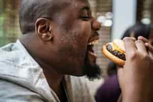 Free photo man eating a big hamburger