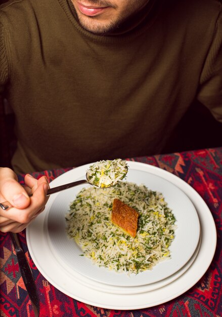 Chigirtma sebzi plovを食べる男、野菜とハーブ添えご飯