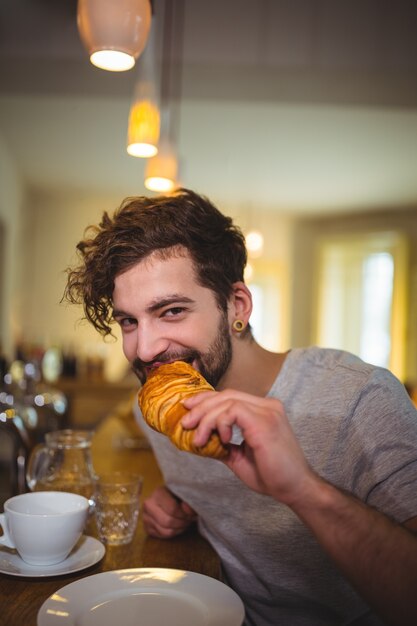 Man eating a croissant in cafÃ©