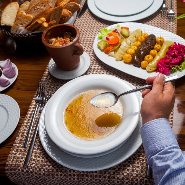 木製のテーブルに肉とおいしい東部エンドウ豆のスープを食べる人。ハイアングル。