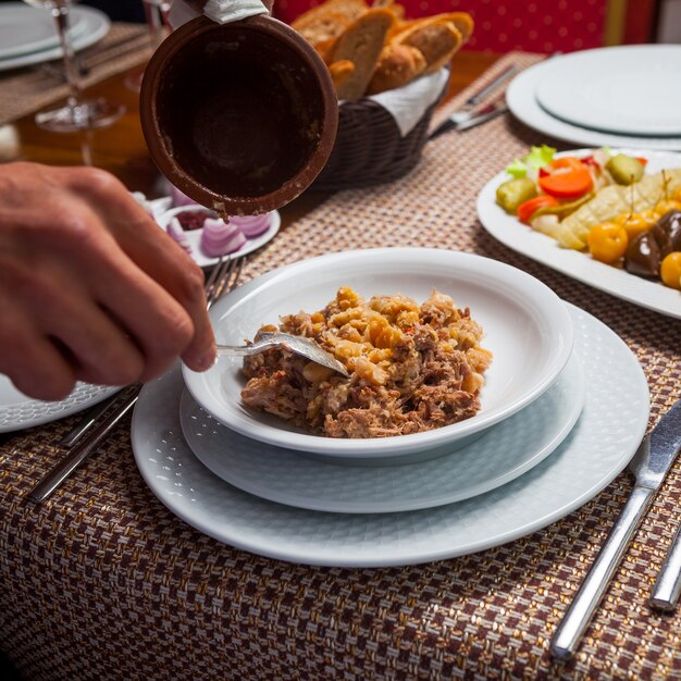 木製のテーブルに肉とおいしい東部エンドウ豆のスープを食べる人。ハイアングル。