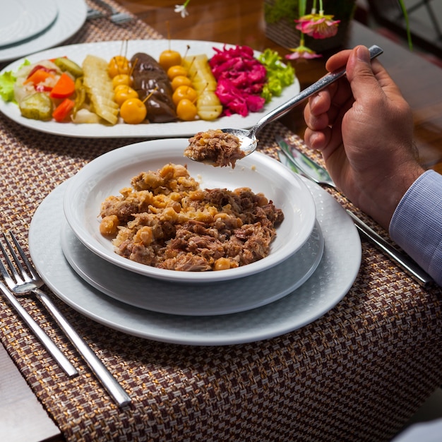 木製のテーブルに肉とおいしい東部エンドウ豆のスープを食べる人。ハイアングル。