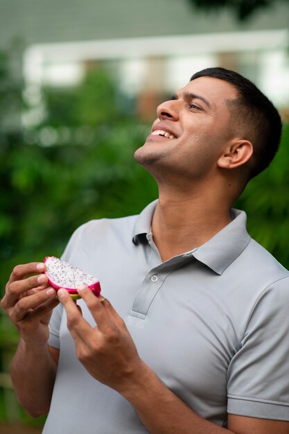 Free photo man eating dragon fruit outdoors