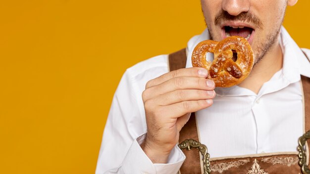 Man eating german pretzel with yellow background