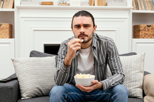 Человек ест попкорн и смотрит телевизор