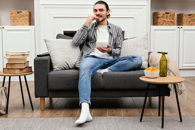 Man eating popcorn and watching tv long shot