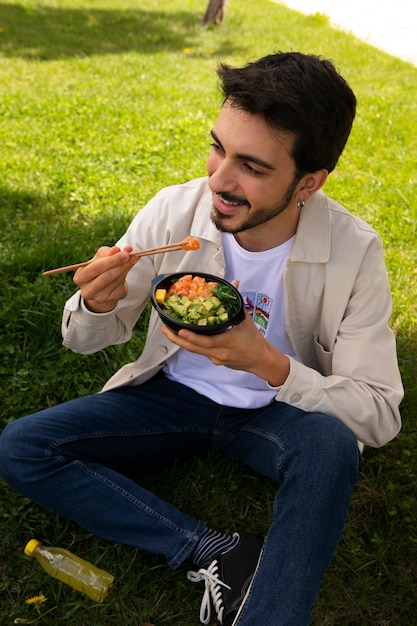 Foto gratuita ciotola di piatto di salmone mangiatore di uomini sull'erba all'aperto