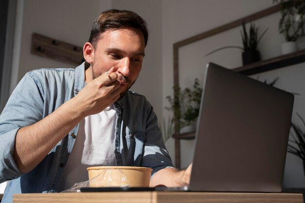 持ち帰り用の食べ物を食べてノートパソコンを使用している