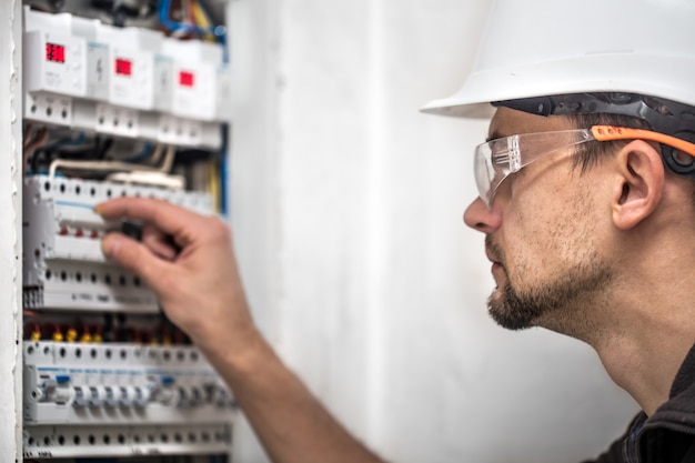 Man, an electrical technician working in a switchboard with fuses. Installation and connection of electrical equipment. Close up.