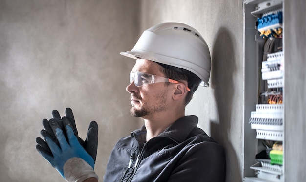 Foto gratuita l'uomo, un tecnico elettrico che lavora in un centralino con micce. installazione e collegamento di apparecchiature elettriche.