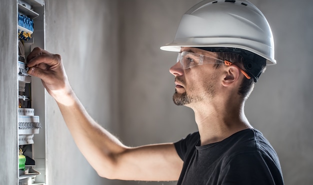 L'uomo, un tecnico elettrico che lavora in un quadro elettrico con fusibili. installazione e collegamento di apparecchiature elettriche.