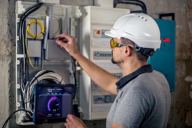 Free photo man an electrical technician working in a switchboard with fuses uses a tablet