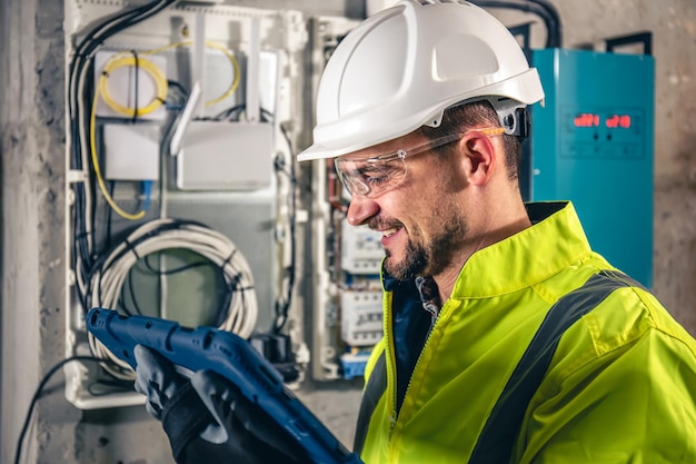 Man an electrical technician working in a switchboard with fuses uses a tablet