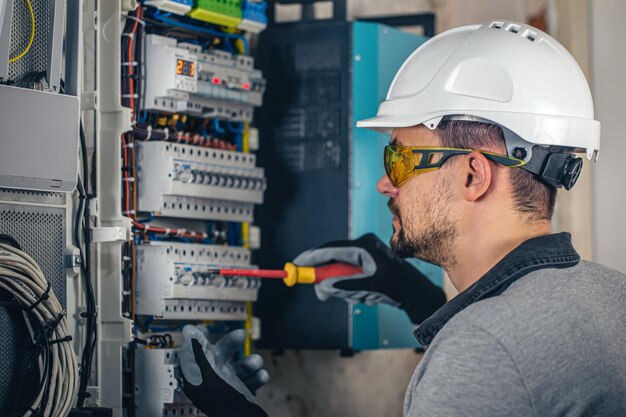 Man an electrical technician working in a switchboard with fuses