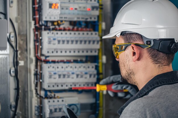 Man an electrical technician working in a switchboard with fuses