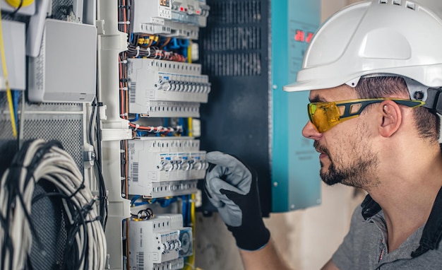 Man an electrical technician working in a switchboard with fuses