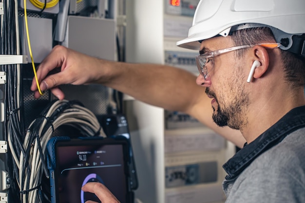 Man an electrical technician working in a switchboard with fuses