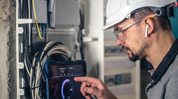 Man an electrical technician working in a switchboard with fuses