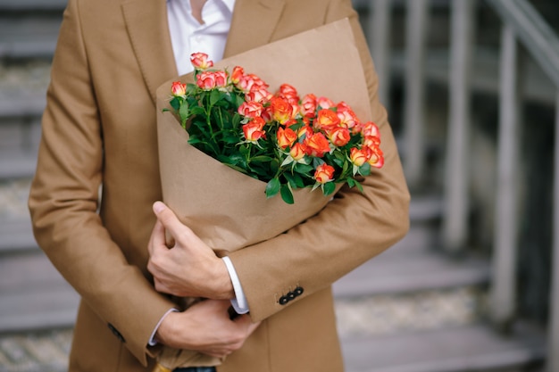 Man embracing a bouquet of flowers, folded in craft paper.