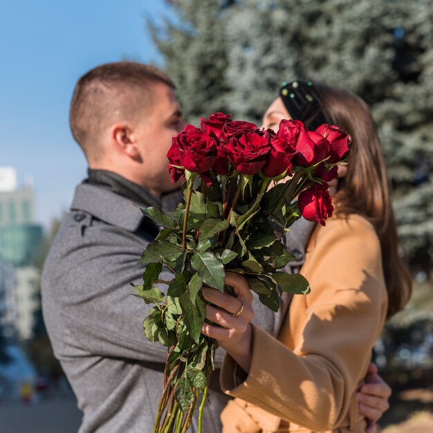 Man embracing and kissing woman with flowers 