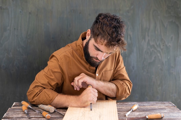 Man engraving in wood outdoors