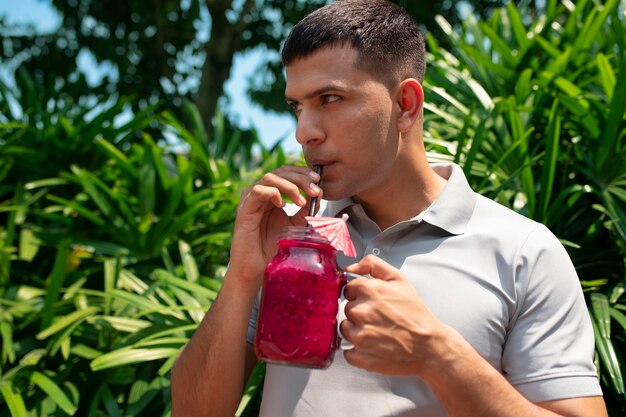 Free photo man enjoying a dragon fruit drink outdoors