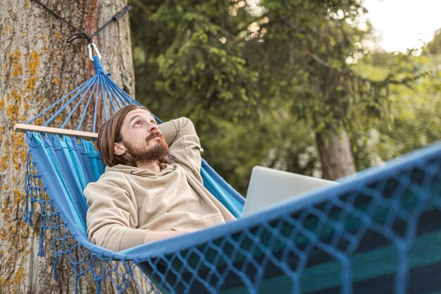 ハンモックに座っている間自然の中で彼の時間を楽しんでいる男