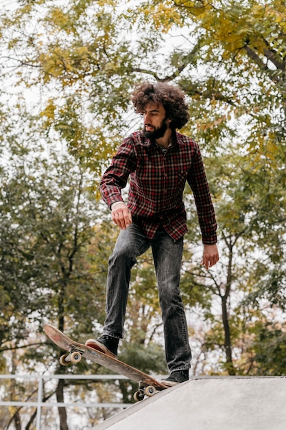 Free photo man enjoying skateboarding in the park