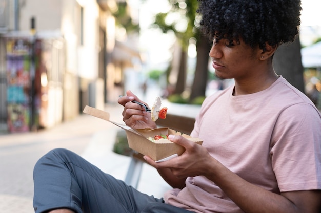 無料写真 屋外でテイクアウトの食べ物を楽しんでいる男