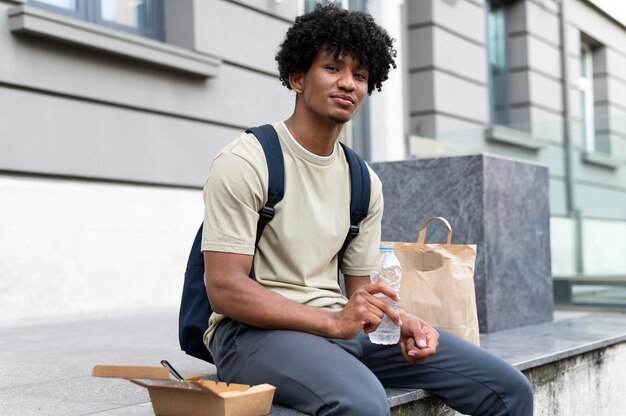 屋外でテイクアウトの食べ物を楽しんでいる男