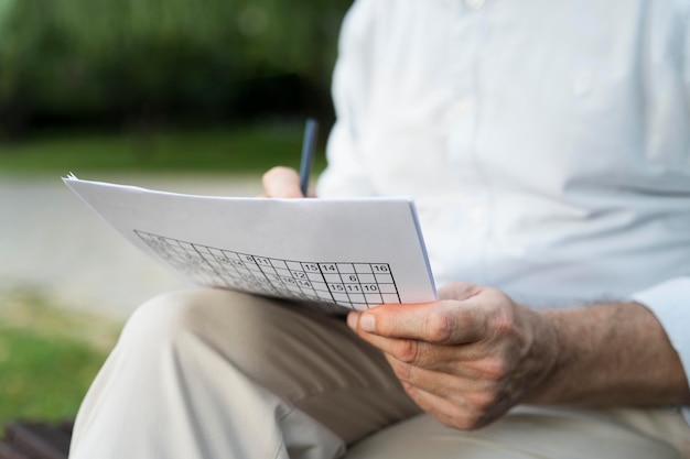 Free photo man enjoying a sudoku game on paper by himself