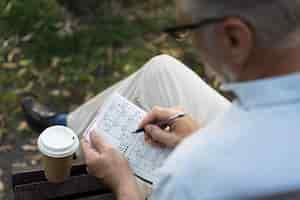 Foto gratuita uomo che si gode da solo un gioco di sudoku su carta