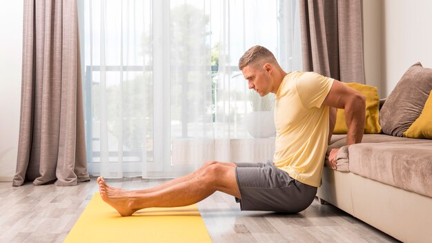 Man exercising at home using couch