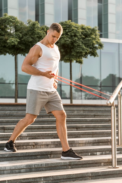 Man exercising with a red stretching band outside