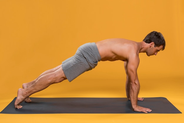 Foto gratuita uomo che si esercita sulla stuoia di yoga