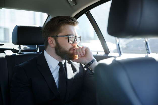 車の後部座席に座っている眼鏡の男