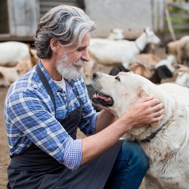 Foto gratuita uomo in fattoria che gioca con il cane