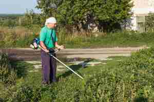 Foto gratuita uomo all'erba di cucito dell'azienda agricola con la falciatrice da giardino