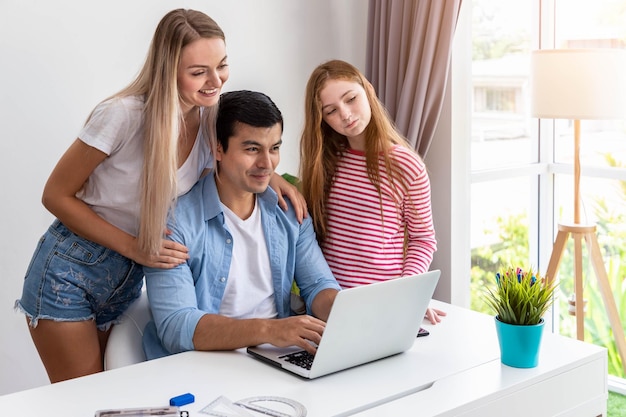 Мужчина или отец работают дома, используя компьютерный ноутбук, а дочь обнимает мать женщины