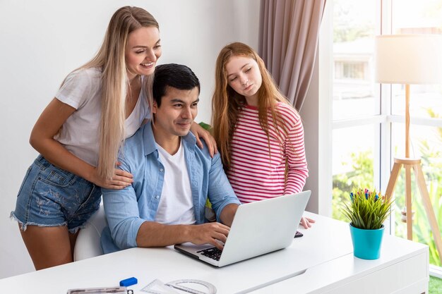 Man or father is working at home using computer notebook with daughter embrace by woman mother