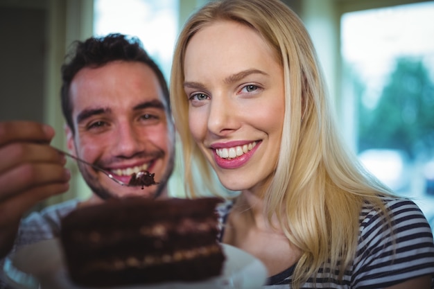 Man feeding pastries to woman in cafÃ©