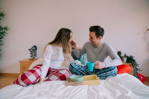 Man feeding woman on bed