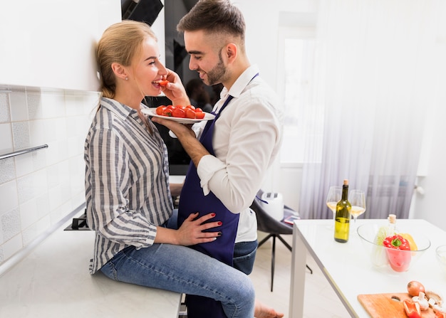 Man feeding woman with tomatoes 