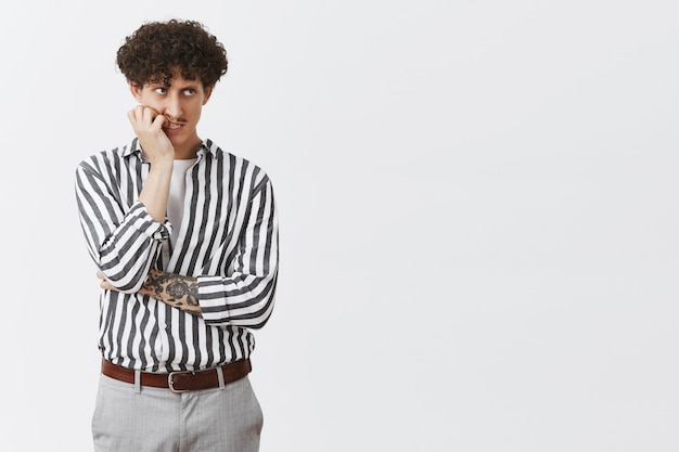 Man feeling jealous and angry coworker got promoted instead of him biting fingernails from disappointment and anger looking from under forehead at upper left corner looking sick and concerned