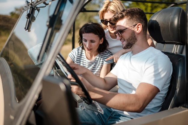 Man and female friends checking map while traveling by car