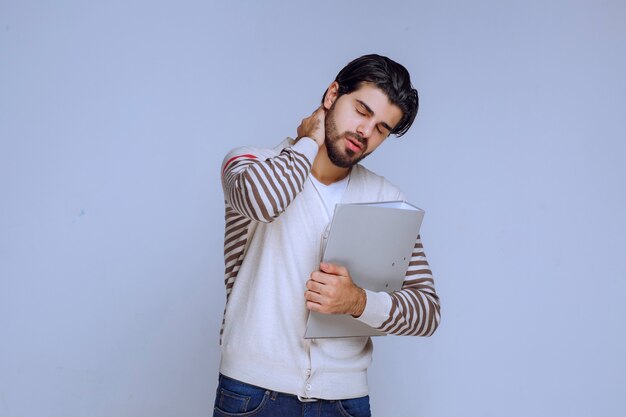 Man finished the project, holds the folder and looks sleepy as he is tired.