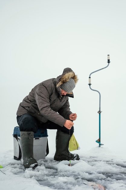 Foto gratuita uomo che pesca da solo fuori in inverno