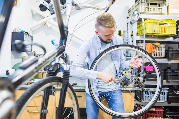 Man fixing bicycle tire with wrench in workshop