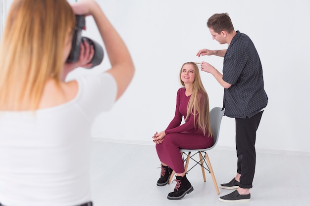 Man fixing the hairstyle on a model in a studio