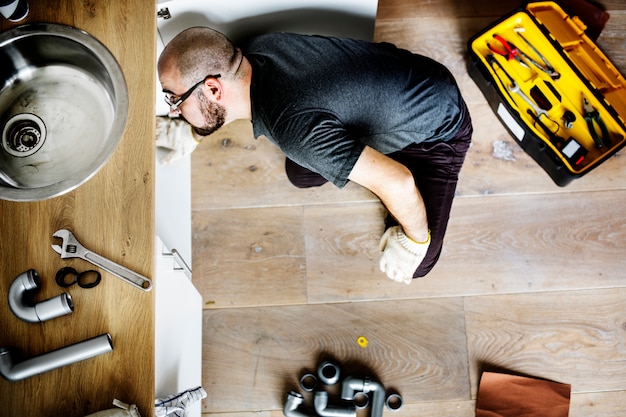 Free photo man fixing kitchen sink